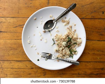 Empty Dish With Spoon And Fork After Eating On The Wooden Table. Top View Of Empty Plate, Dirty After The Meal Is Finished