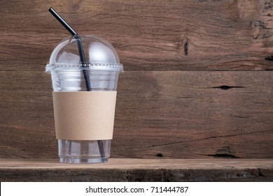 Empty Disposable Cold Coffee Or Drink Cup Have Blank Brown Cardboard Sleeve And Straw On Old Wood Shelf Background