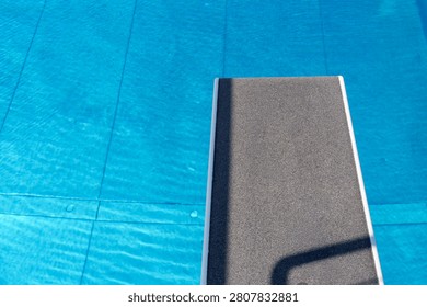 Empty diving board over blue swimming pool water