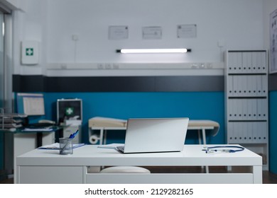 Empty Doctor Office With Nobody In It Equiped With Medical Equipment Having Laptop On Desk. Modern Hospital Clinic Room With Contemporary Furniture. Patient Document On Computer Screen