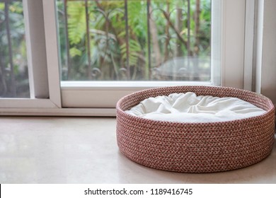 An empty dog/cat bed basket next to window with copy space