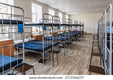 Empty dormitory room with bunk beds in daylight.
