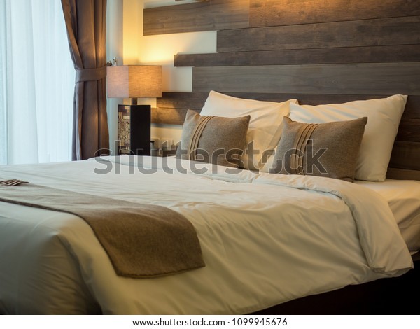 Empty double\
bed and lamp on side of bed in luxury and natural style bedroom is\
decorated with wooden\
boards.\
