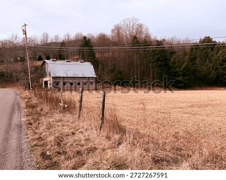 An empty drive-through barn with a classic tin roof sits at the foot of Bullfrog Road,  Trade, TN 2025