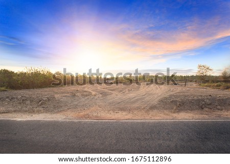 Empty dry cracked swamp reclamation soil, land plot for housing construction project with car tire print in rural area and beautiful blue sky with fresh air Land for sales landscape concept