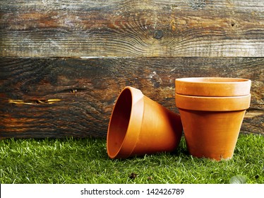 Empty earthenware terracotta flower pots on a trimmed green lawn against the wall of a wooden garden shed with copyspace - Powered by Shutterstock