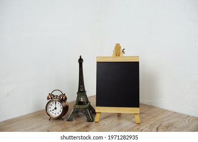 Empty Easel Chalkboard Sign Mockup With Alarm Clock And Eiffel Souvenir