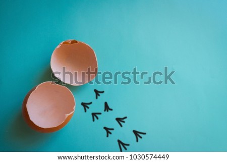 Empty eggshell, next to a chain of tracks. Everything has its time, its own way, growing up of children. Blue background, top view. The picture is made by the author.