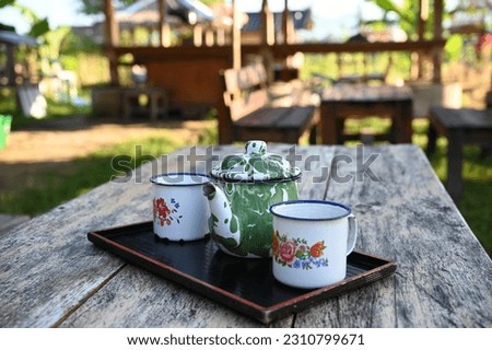 Empty enamel mugs and enamel teapot on wooden table. Selective Focus.