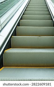 Empty escalator steps lead upward. Modern design with glass sides and yellow edges. Clean, repetitive lines create sense of motion. Great for urban, transit, or commercial themes
