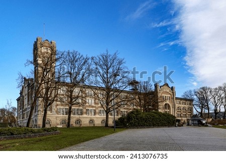 Empty esplanade with old main building of former Waterschei mine in background against blue sky, bare trees, Thor Park - Hoge Kempen National Park, sunny autumn day in Genk, Belgium