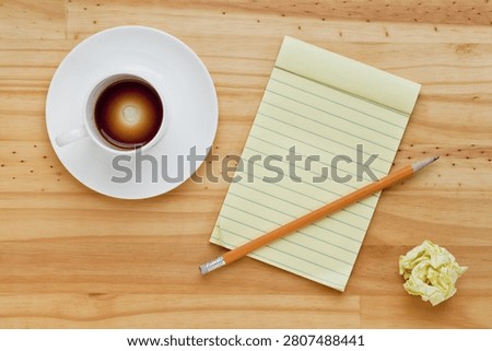 Empty espresso coffee cup, notepad and pencil on pine wood table