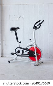 empty exercise machine on a white background with red elements stands on a concrete floor white brick wall orbitrek