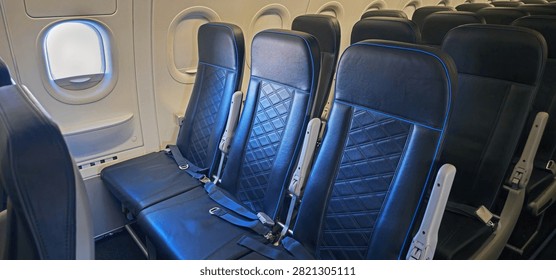 Empty exit row seats inside a commercial airplane cabin with aircraft windows and extra legroom. Ideal for concepts related to airline travel, aviation, passenger comfort, emergency exits, transportation, and commercial aircraft interiors.