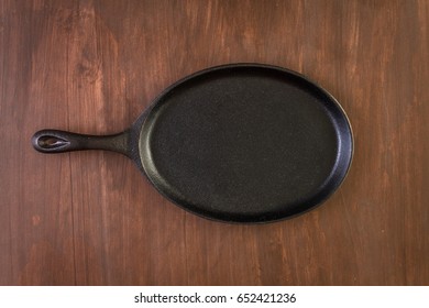 Empty Fajita Cast Iron Skillet On A Wood Background.