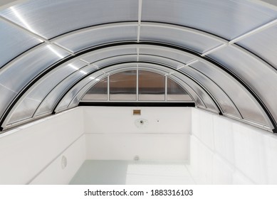 An Empty Fiberglass Swimming Pool With A Sliding Polycarbonate Cover On A Sunny Spring Day. A Pool Is White-colored, While The Pavilion Is Half-transparent With Blue Toning.