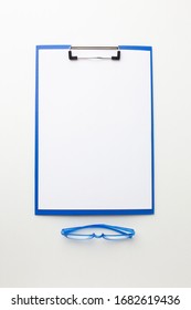 Empty File Folder On White Desk With Glasses For Sight. Top View.