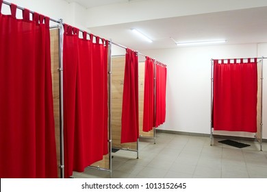 Empty fitting rooms with red curtains and white walls. Dressing rooms in clothing store with no people