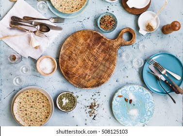 Empty food table. Green blue empty ceramic plate with silver spoon and old round cutting board arranged over turquoise color table with salt pepper bowl. - Powered by Shutterstock