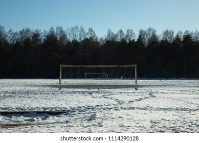 Empty Football Field Covered In Snow With A Treeline Behind