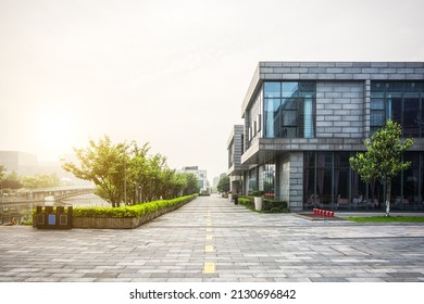 Empty Footpath With Modern Office Building Exterior And Blue Cloudy Sky During Sunrise