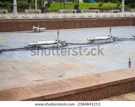 Empty fountain in a city park. Dehumidification. Cleaning the fountain with a hose. The device of the fountain. Pipes for water supply. Water hoses. Modern technologies. Infrastructure maintenance.