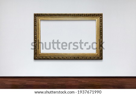 Empty frame on white wall in Museum. place for pictures. Antique Framework. Vintage picture frame on white wall.