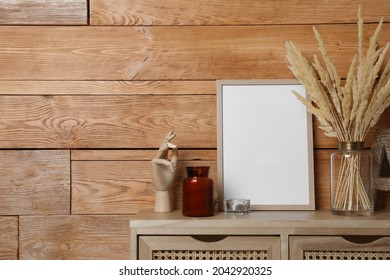 Empty frame with other decor on table near wooden wall. Mockup for design