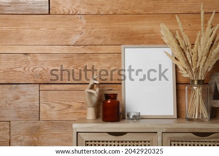 Empty frame with other decor on table near wooden wall. Mockup for design