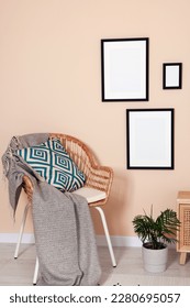 Empty frames hanging on beige wall, wicker chair and potted plant indoors - Shutterstock ID 2280695057
