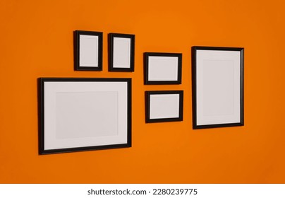 Empty frames hanging on orange wall. Mockup for design