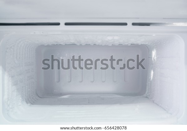 empty freezer of a refrigerator - Ice buildup on\
the inside of a freezer walls.\
