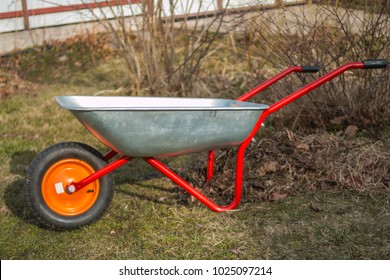 empty garden trolley, wheelbarrow.Old metal trolley on dry grass. Spring in garden. Spring season.cleaning of the garden area, Park. preparation of the garden for planting. Cope space