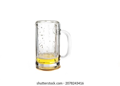 A empty glass beer stein with a bit of beer left and remaining flecks of foam isolated on white - Shutterstock ID 2078243416