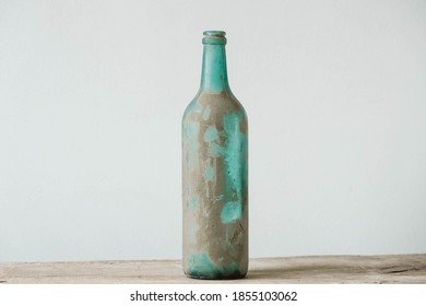 Empty glass bottle in dirt on a wooden table. Copy, empty space for text