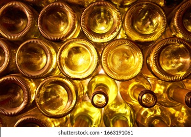        Empty glass bottles - wine or beer - beautifuly lit byt the sunshine stacked on one another.                     
