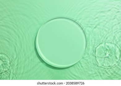 Empty Glass circle podium on transparent clear green water texture with splashes and waves in sunlight. Abstract nature background for product presentation. Flat lay cosmetic mockup.