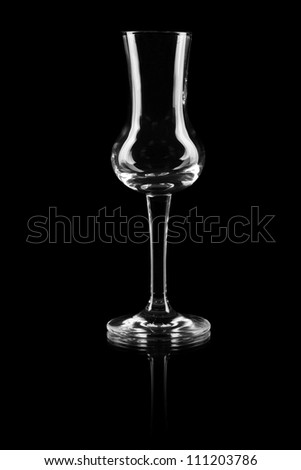 Empty glass on a reflective surface on black background