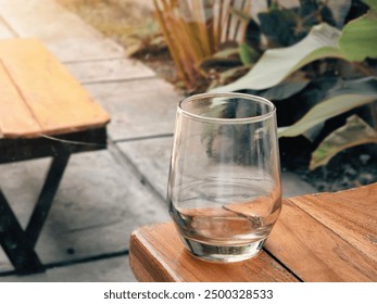 An empty glass on a café table with space for a menu or promotional material, set in a lifestyle context.