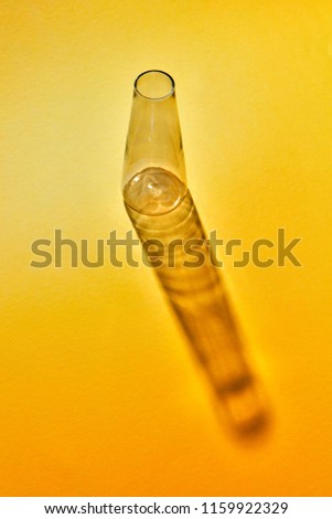 Empty glass transparent bottle with reflection on a yellow paper background, copy space. laboratory glasses at experiment in chemistry laboratory