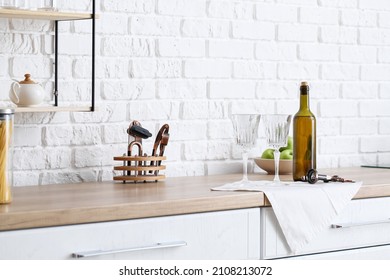 Empty Glasses And Bottle Of Wine On Kitchen Counter Near White Brick Wall