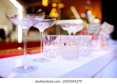 empty glasses stand in rows on the bar counter. Clean the empty glasses on the counter. Empty glasses on the bar. Ready to celebrate the party. A close-up of empty glasses in a bar.