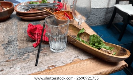 Empty glasses and vibrant remnants post feast, hinting at Dia de los Muertos merriment, urban nostalgia, culinary tales unfolding
