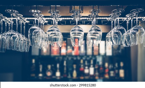 Empty glasses for wine above a bar rack in vintage tone.