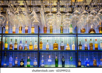 Empty Glasses For Wine Above A Bar Rack With Colorful And Many Of Liquor Bottles On The Shelf.