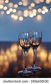 Empty Glasses Of Wine On Glass Table With Bokeh Background Close Up. New Year, Christmas Mood. Greeting Card. Party And Holiday Celebration Concept.