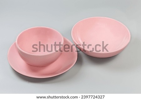 Empty glazed ceramic pink deep bowl for serving food and dining on the flat service plate and wide shallow bowl separately on a gray background