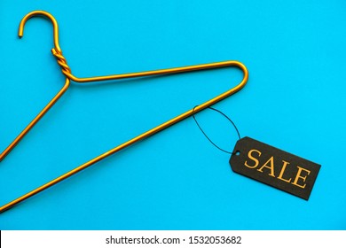Empty Gold Hanger Rack With Label Tag On Bright Blue Color Table Background, Male Female Retail Clothes Fashion Store Shopping Sale Promotion Cheap Black Friday Offer Concept, Top Close Up View
