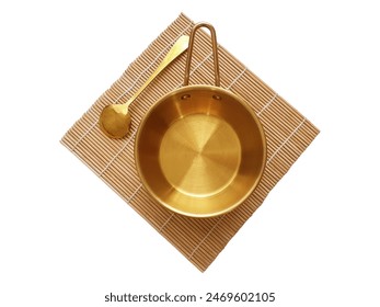 Empty golden bowl with handle and gold spoon on bamboo mat isolated on white background with clipping path. Top view, flat lay. Mockup template for food poster design.