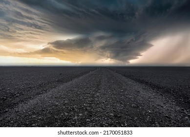 Empty gravel pathway on lava sand in Highland desert. Scenic view of famous black beach. Beautiful scenery of volcanic landscape against dramatic sky during sunset. - Powered by Shutterstock